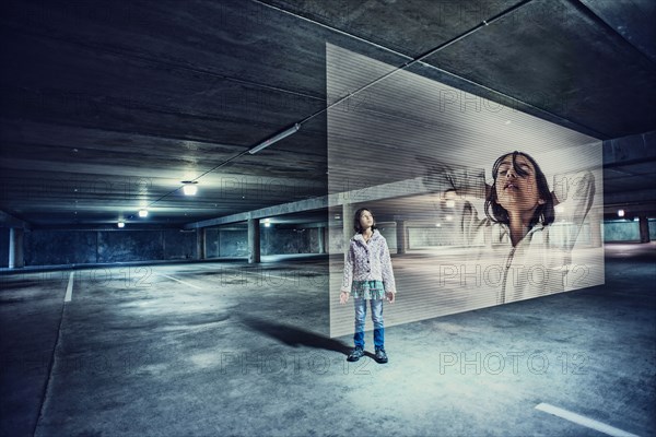 Mixed race girl watching holographic screen in parking lot