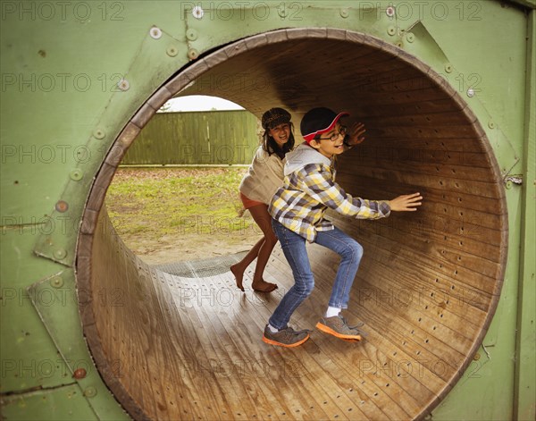 Mixed race children playing in wheel in playground