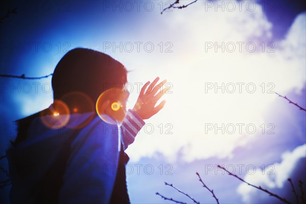 Mixed race girl shielding herself from sun lens flare
