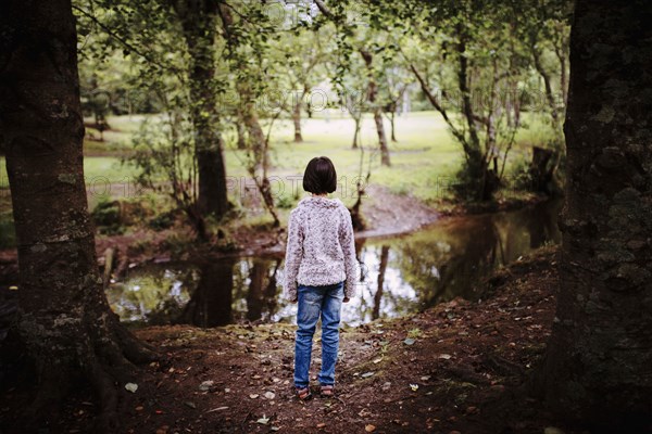 Mixed race girl standing near still creek