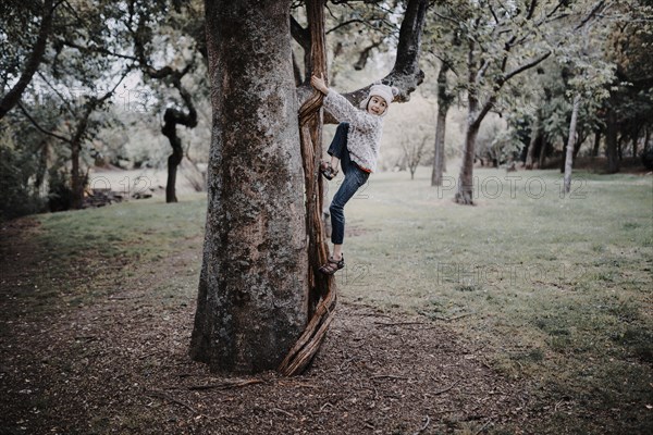 Mixed race girl climbing tree in park