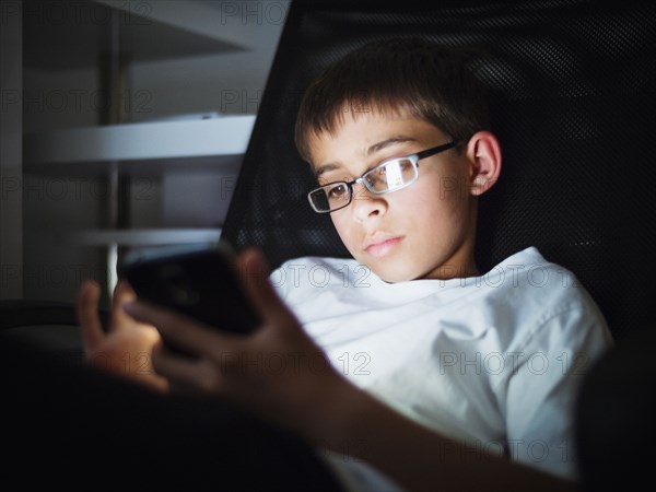 Mixed race boy texting on cell phone at night