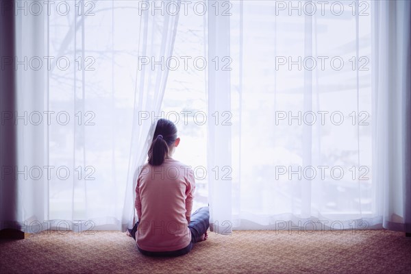 Mixed race girl sitting on floor near window