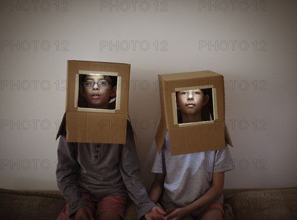 Mixed race brother and sister wearing cardboard box astronaut helmets