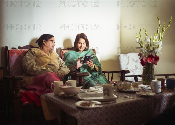 Mother and daughter using cell phone at dinner table