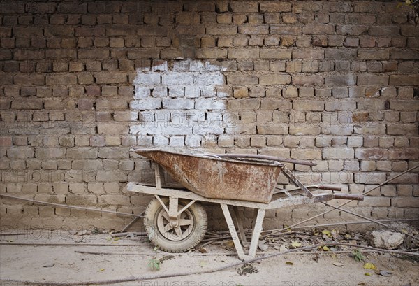 Empty wheelbarrow near brick wall