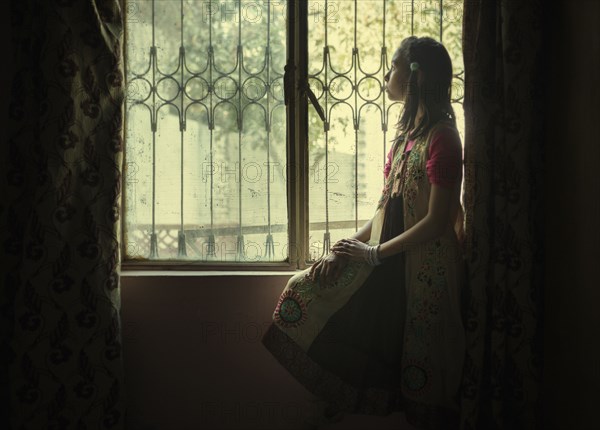 Mixed race girl looking out window