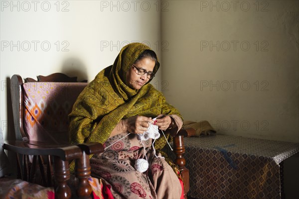 Older woman knitting baby clothes