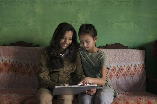 Aunt and niece using digital tablet on sofa