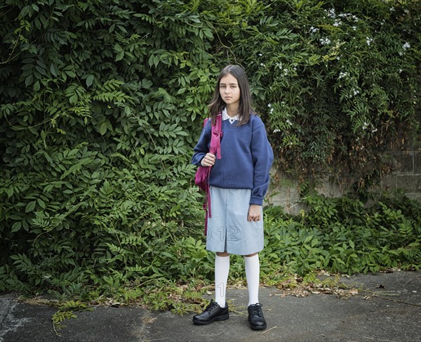 Mixed race schoolgirl in uniform with backpack