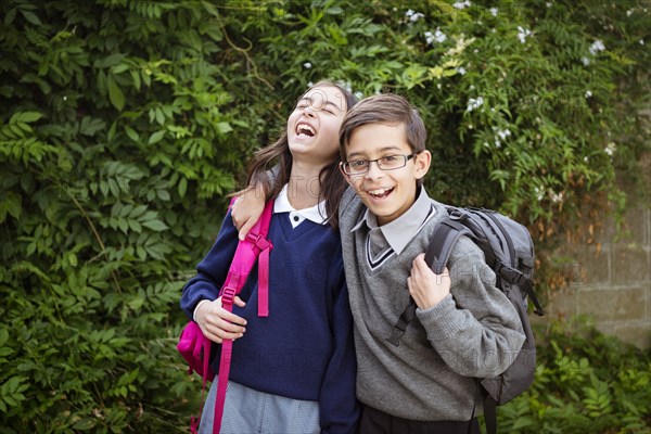 Mixed race brother and sister laughing in school uniforms