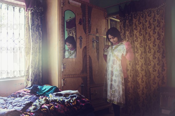 Mixed race woman examining dress in bedroom