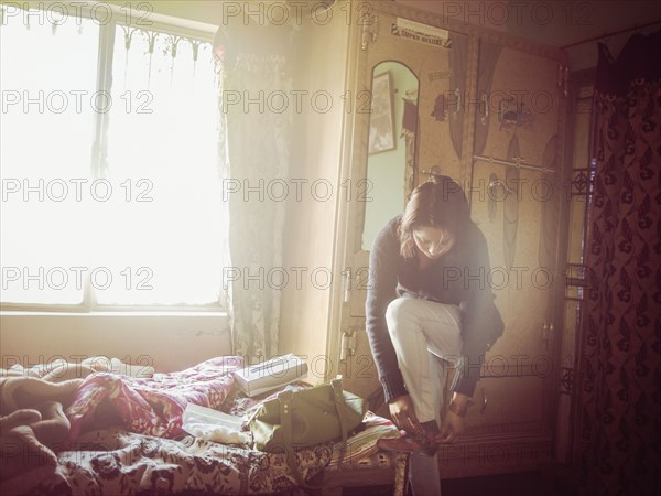 Mixed race woman dressing in bedroom