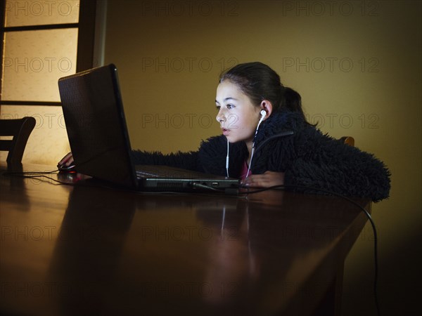 Mixed race girl using laptop at table night