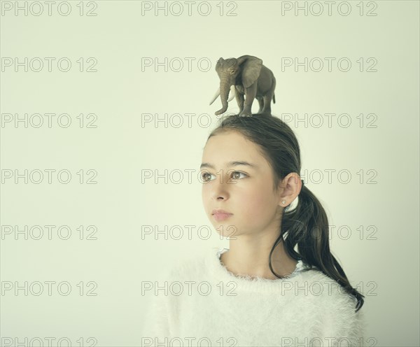 Mixed race girl holding toy elephant on head