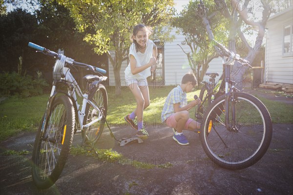 Mixed race children fixing bicycles in backyard