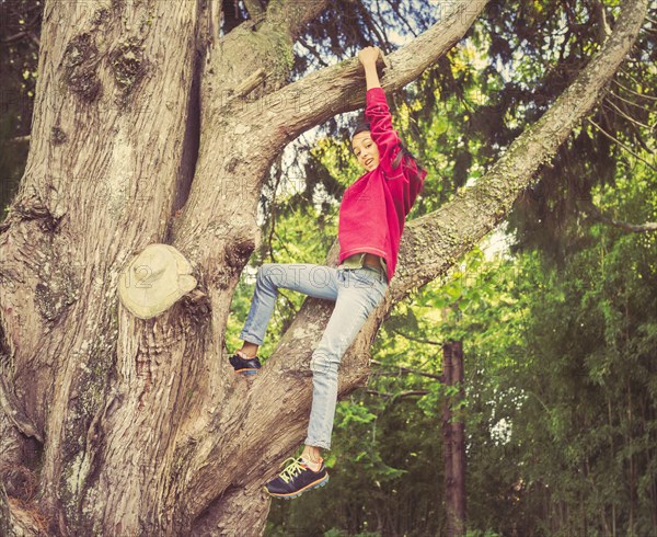 Mixed race girl climbing tree