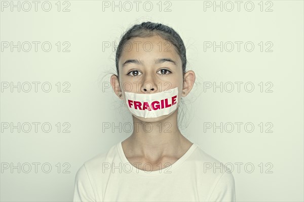 Mixed race girl wearing fragile sticker over mouth