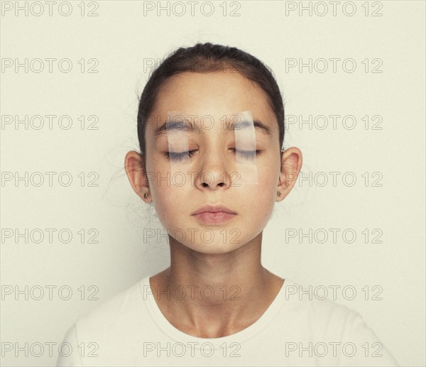Mixed race girl with eyes taped shut