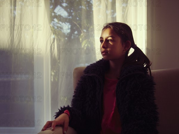 Mixed race girl sitting on sofa in living room