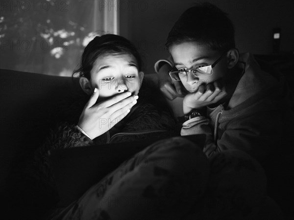 Mixed race children using digital tablet at night