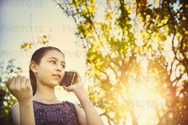 Mixed race girl talking on cell phone outdoors