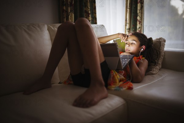 Mixed race girl using digital tablet on sofa