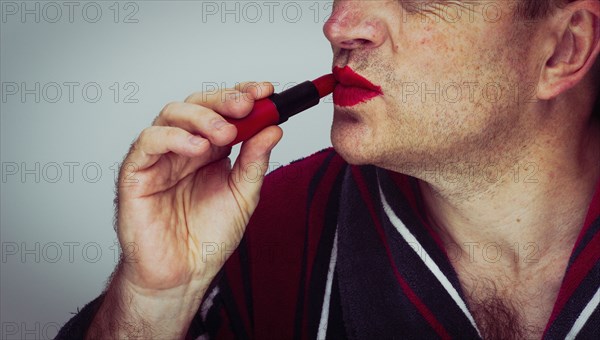 Caucasian man applying lipstick