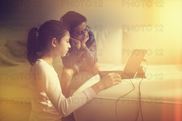 Mixed race children using laptop on sofa