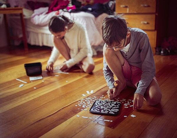 Mixed race children doing puzzles on bedroom floor