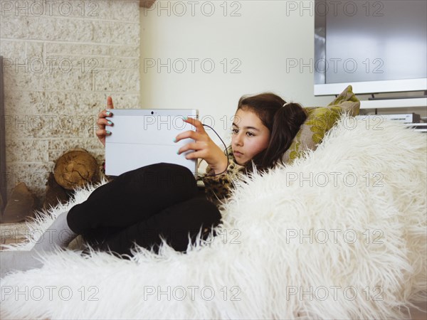 Mixed race girl using digital tablet in bean bag