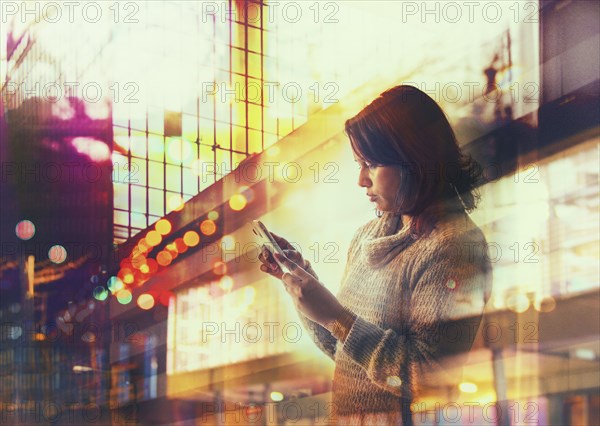Woman using cell phone in city at night