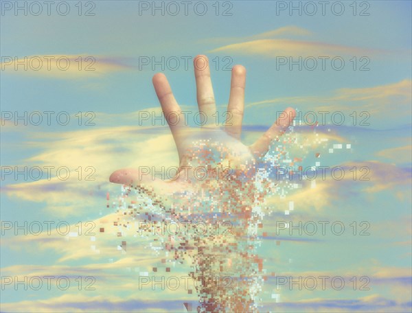 Pixelated hand dissolving in sky