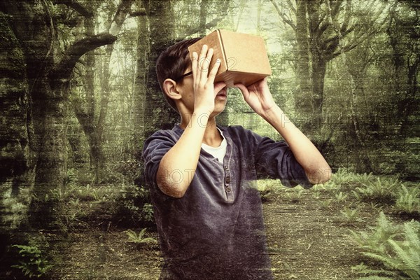 Mixed race boy peering in box in forest