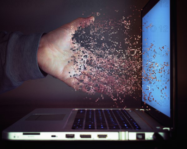 Pixelated hand of Caucasian man dissolving into laptop screen