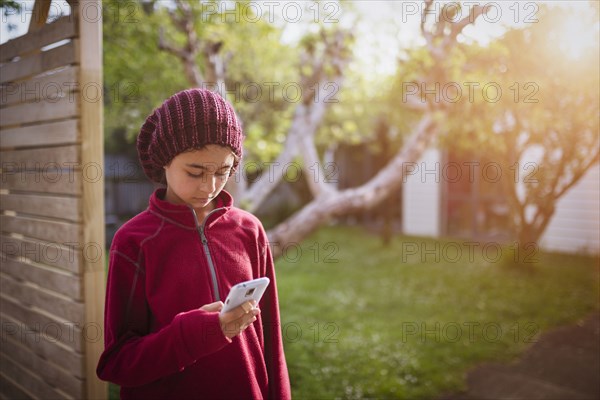 Mixed race girl using cell phone in backyard