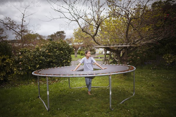 Mixed race girl standing in broken trampoline