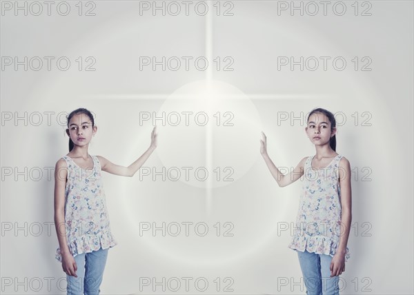 Mirror image of mixed race girl reaching for light