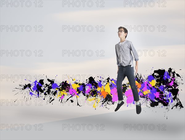 Mixed race boy jumping with paint splatters