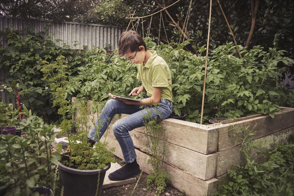 Mixed race boy using digital tablet in garden