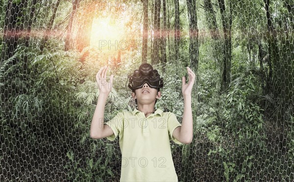 Mixed race boy wearing virtual reality goggles in remote forest