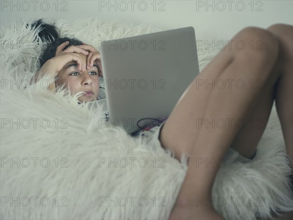 Mixed race girl using laptop in beanbag chair