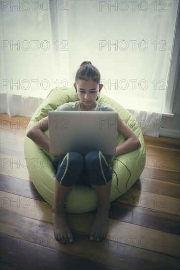 Mixed race girl using laptop in beanbag chair