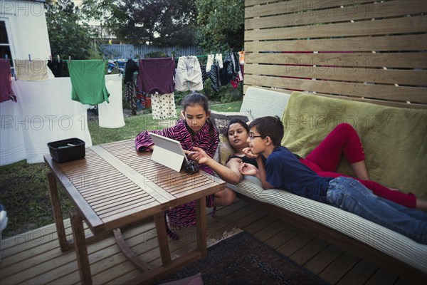 Mother and children using digital tablet in backyard