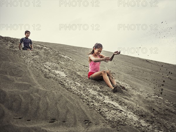 Children sliding on sand dune