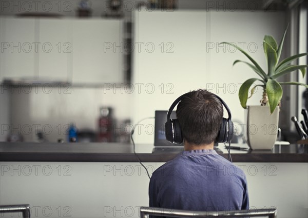 Mixed race boy listening to headphones in kitchen