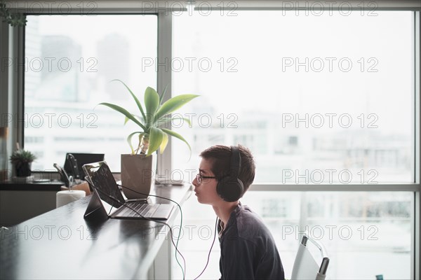 Mixed race boy listening to headphones in kitchen