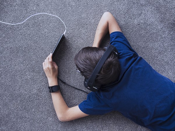 Mixed race boy using cell phone on floor