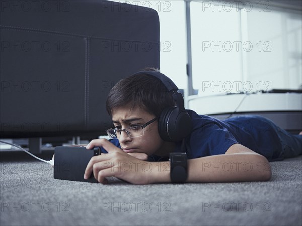 Mixed race boy using cell phone on floor