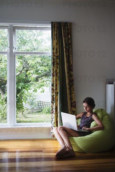 Mixed race girl using digital tablet in beanbag chair